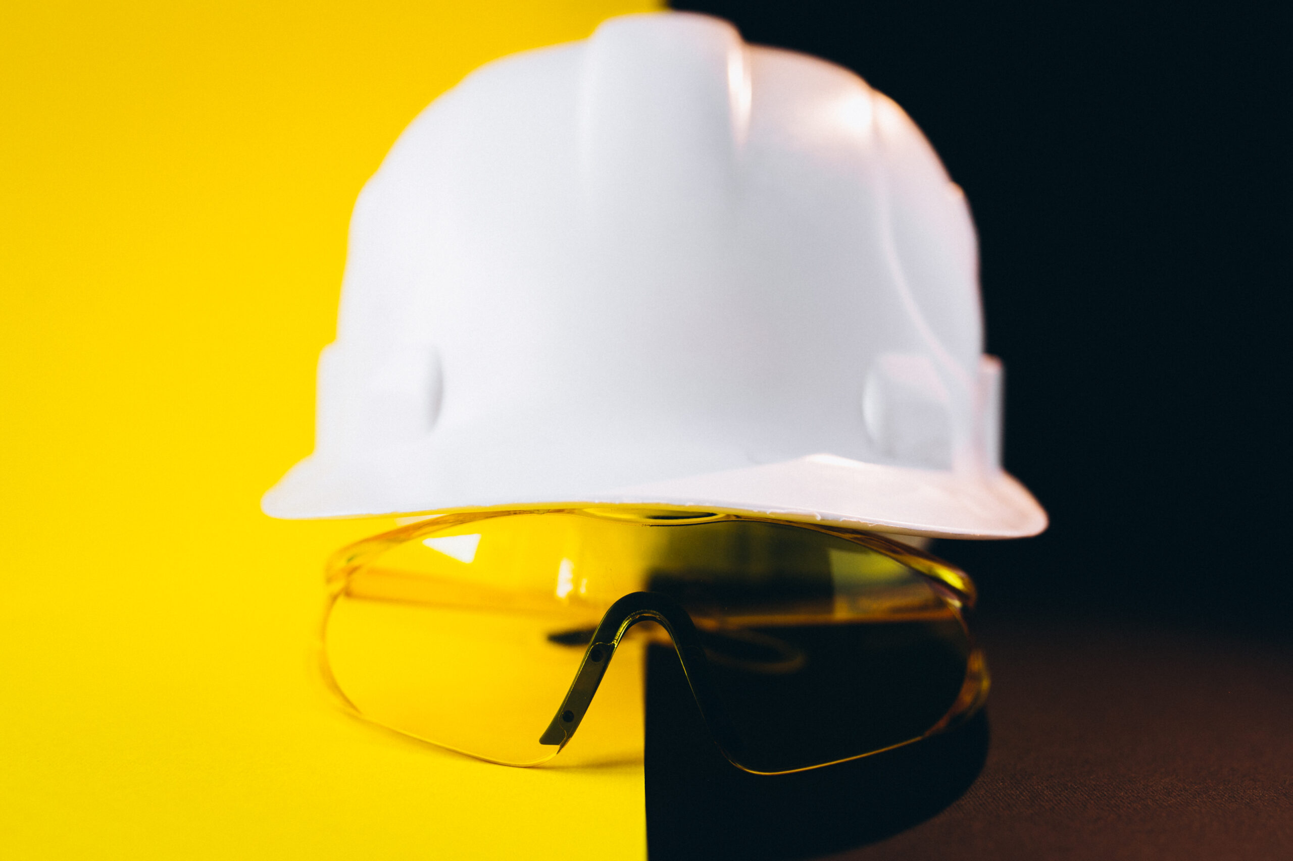 White hard hat with protection eyeglasses isolated on a black and yellow background DPI 3° CATEGORIA